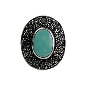 A turquoise stone is surrounded by black stones.